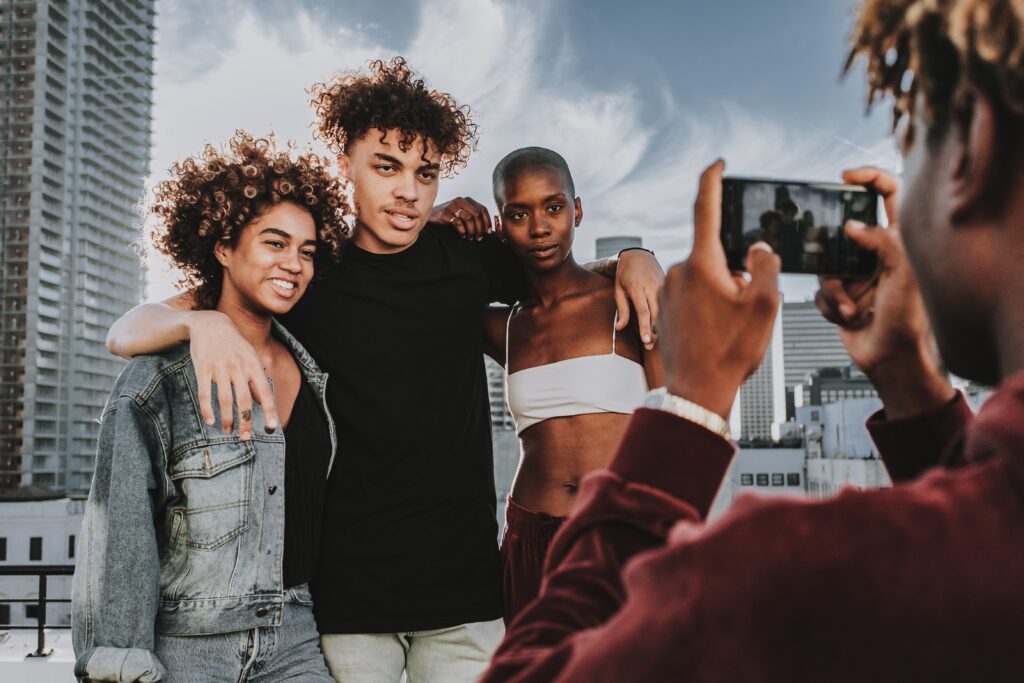 Influencer capturing three friends posing on a rooftop with a cityscape, illustrating the concept of influencer marketing strategies and social media engagement.